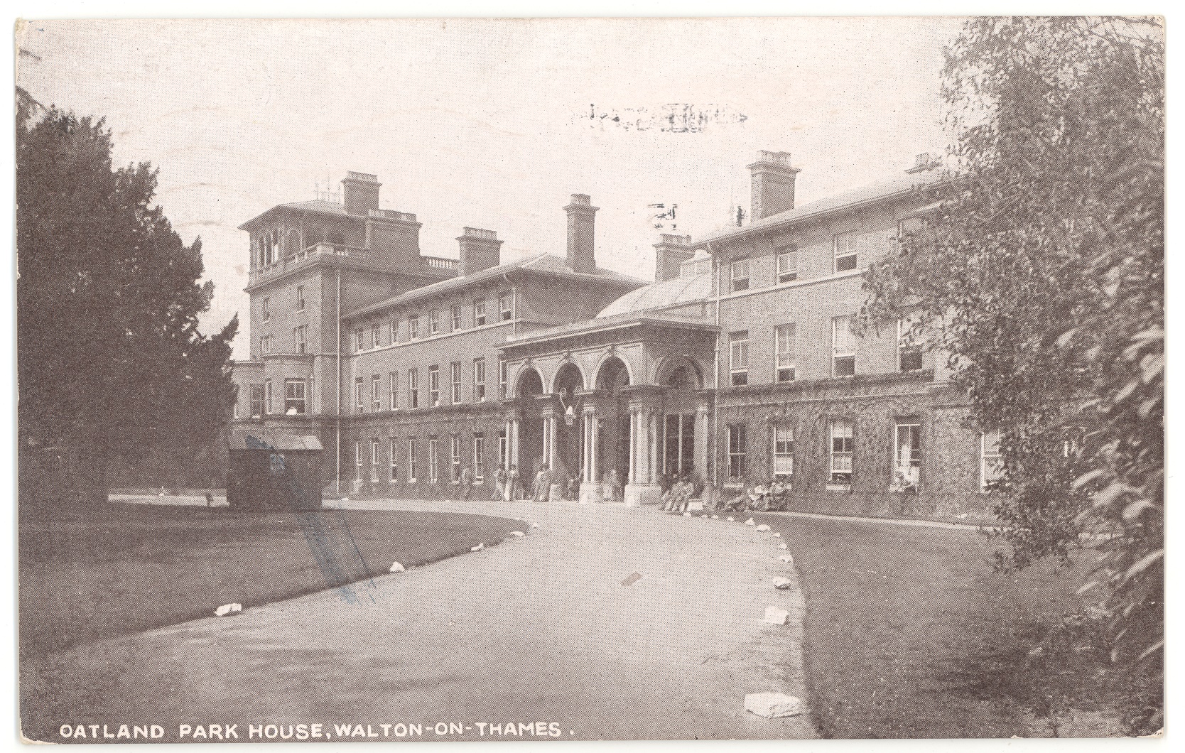 Black and white postcard of Oatlands Park Hotel, showing the curved drive to the porticoed entrance with New Zealand soldiers sitting and standing outside, October 1915.